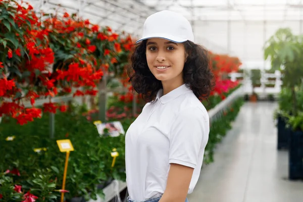 Smiling young woman walking in greenhouse. — Stock Photo, Image