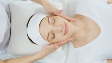 Masör güzel genç bir bayan için yüz masajı yapıyor.. 