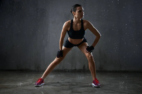 Sportlerin beim Seitfallzieher im Regen. — Stockfoto