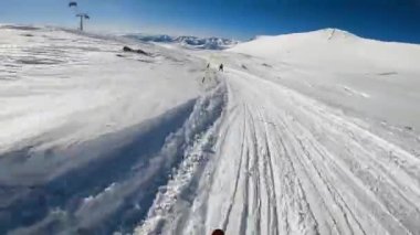 Karlı yamaçlarda kayakçılar.