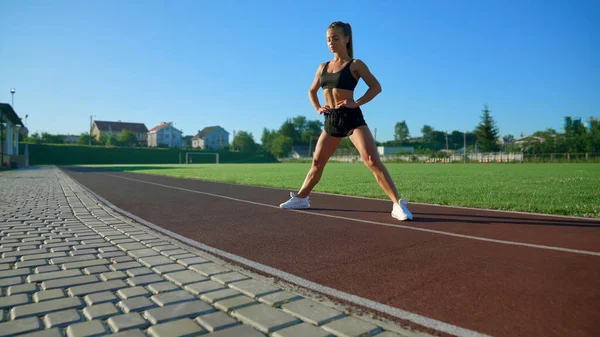 Fit kobieta stojąca z nogami szeroko na stadionie. — Zdjęcie stockowe