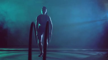 Kaslı esmer kadın iplerle antrenman yapıyor..