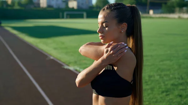 Dziewczyna rozgrzewa górną część ciała na stadionie rano. — Zdjęcie stockowe