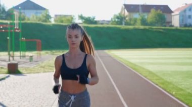 Stadyumda koşup müzik dinleyen bir kadın..