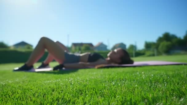Woman practicing floor bridge butt raise exercises on grass. — стоковое видео