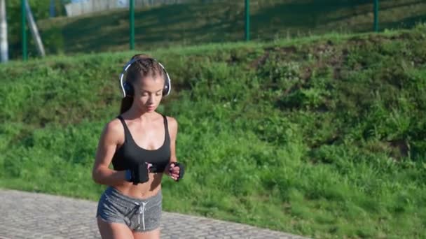 Female runner training at stadium, wearing headphones. — Stock Video