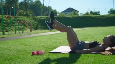 Kadın dışarıda bacak kaldırma egzersizi yapıyor..