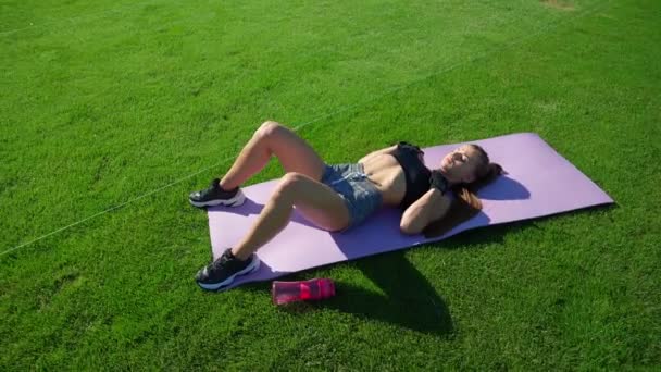 Girl practicing floor bridge butt raise exercise outdoors. — Stok video