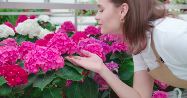 Ung kvinde sniffing smukke lyserøde og hvide blomster. – Stock-video