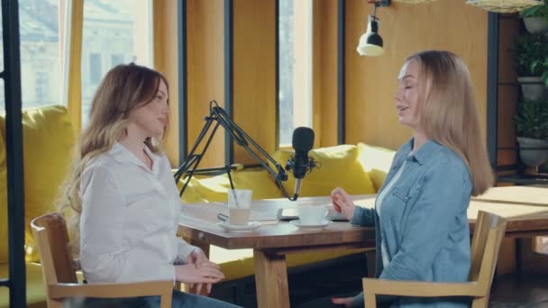 Zwei Frauen benutzen Mikrofon beim Interview im gemütlichen Café — Stockvideo