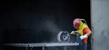 Man using sandblaster for cleaning metal details at work clipart