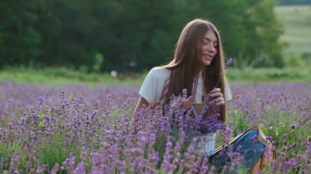 Glimlachend boerenmeisje ruikt bloem in lavendelveld. — Stockvideo