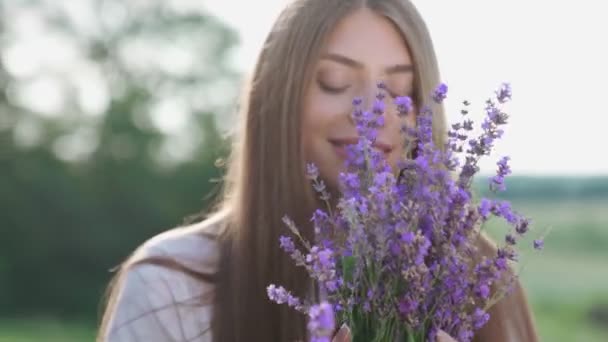 Uśmiechnięta dziewczyna trzyma bukiet na polu lawendy. — Wideo stockowe