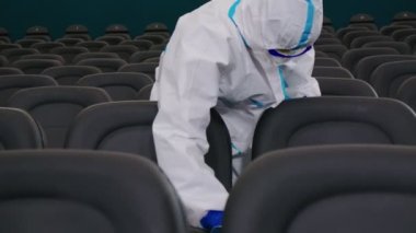 Koruyucu üniformalı işçiler sandalyelere dezenfektan sıkarlar.