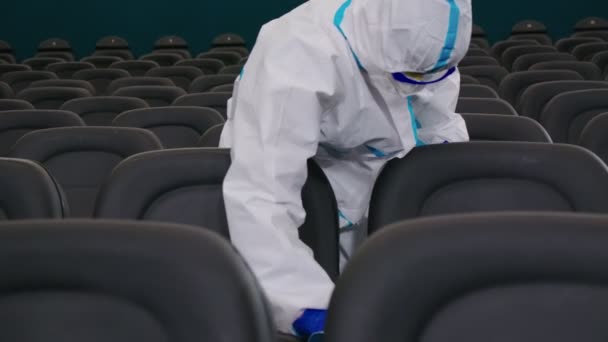 Trabajador en uniforme protector rociando desinfectante en sillas — Vídeo de stock