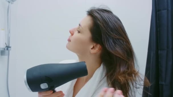 Νεαρή γυναίκα που χρησιμοποιεί στεγνωτήρα μαλλιών μετά το ντους — Αρχείο Βίντεο