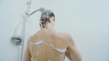 Duşta şampuanla vücudu ve siyah saçları yıkayan bir kadın..