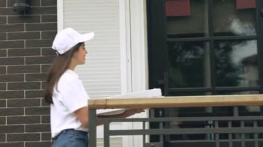 Kadın kurye, adama pizza kutusu veriyor..