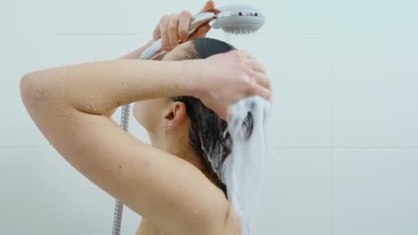 Vrouw wassen donker haar met shampoo onder de douche — Stockvideo