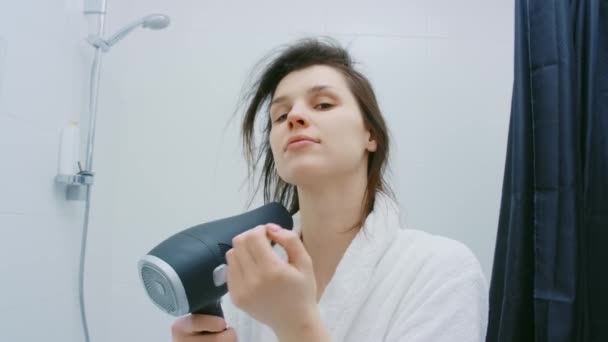 Стоять в ванной и сушить волосы — стоковое видео