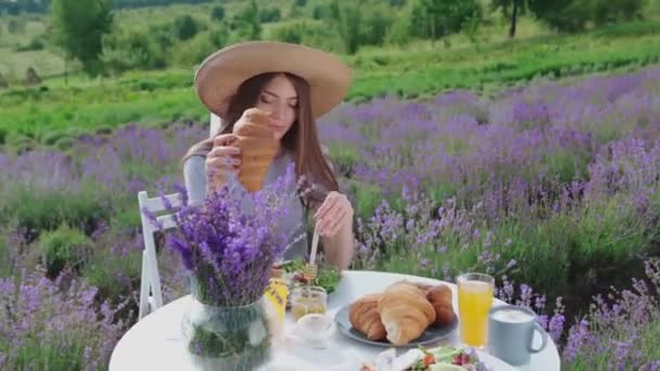 Jovem mulher comer croissant no campo de lavanda. — Vídeo de Stock