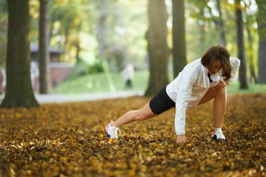Spor yapan kadın dışarıda egzersiz yaparken bacaklarını açıyor.