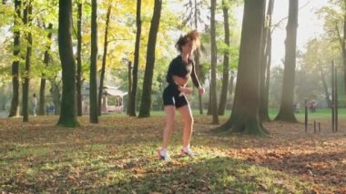 Çekici esmer açık havada burpee yapıyor.