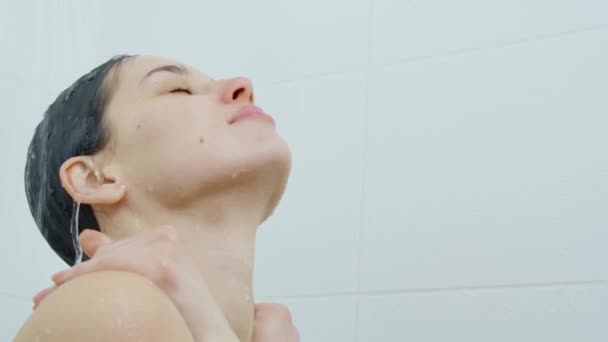 Ung kvinna njuter av processen att duscha i badrummet. — Stockvideo