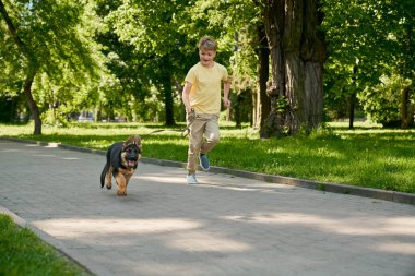 Yeşil Park 'ta koşan neşeli çocuk ve küçük köpek yavrusu
