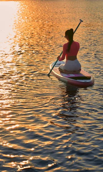 Vrouw zwemmen op sup board met lange peddel in handen — Stockfoto