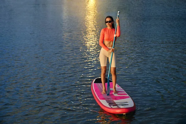 Vrouw met lange peddel voor roeien op sup board — Stockfoto