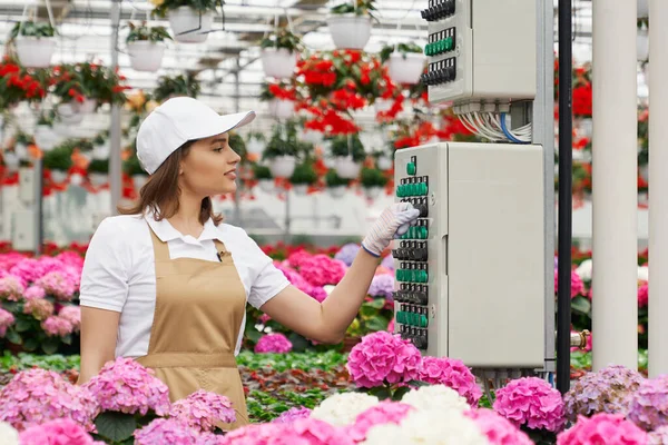 Greenhouse worker using equipment for watering flowers — Stock Photo, Image