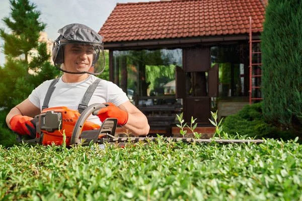 Jardinero usando recortador de setos eléctrico para formar arbustos — Foto de Stock