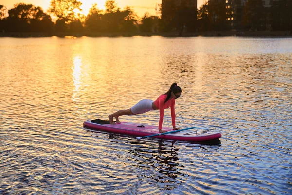 Sterke vrouw staande in plank positie op sup board — Stockfoto