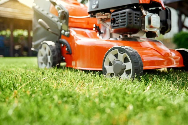 Red lawn mower standing at summer garden — Stock Photo, Image