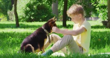 Parkta siyah ve kahverengi köpek yavrusuyla oynayan neşeli çocuk. 