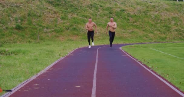 Dos hombres con torso desnudo corriendo juntos en el estadio — Vídeo de stock