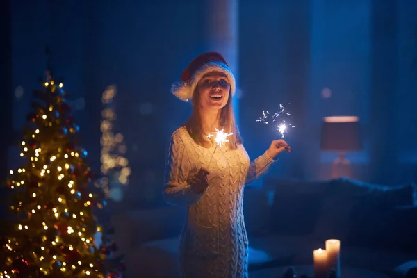 Cheerful woman with sparklers in hands standing at dark room — Stock Photo, Image