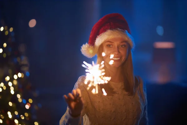 Vrolijke vrouw in kerstmuts met sterretjes in de donkere kamer — Stockfoto