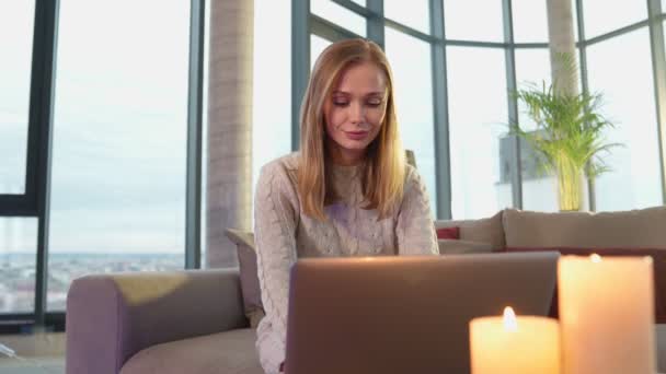 Jovem mulher trabalhando no laptop enquanto se senta no sofá — Vídeo de Stock