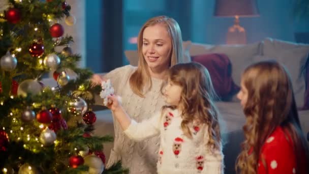 Μικρές αδελφές στολίζουν χριστουγεννιάτικο δέντρο με τη μητέρα τους — Αρχείο Βίντεο