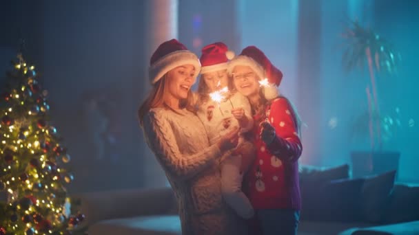 Anne ve kızları Noel Baba şapkası takıyor ve maytap kullanıyorlar. — Stok video