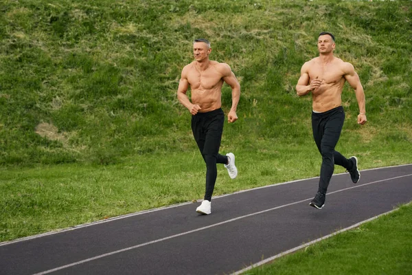 Dos culturistas con torso desnudo corriendo al aire libre — Foto de Stock