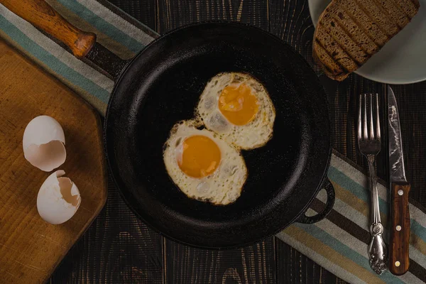 Fried eggs. Close up view of fried eggs in a cast iron pan. Top view with dark background.