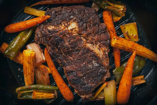 Sebzeli dökme demir bir tavada orta pişmiş pirzola..