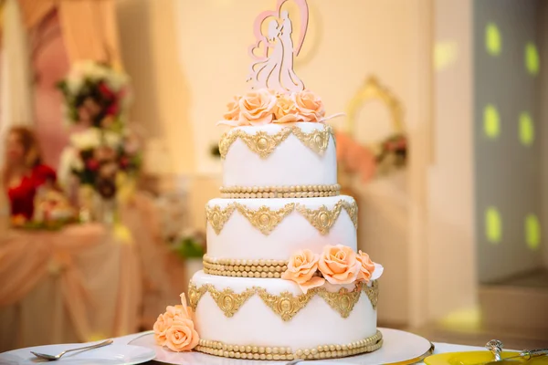 big white wedding cake with the roses on a white table