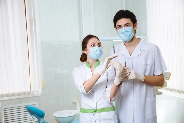 Dentists woman and a man with medical instruments in the dental office