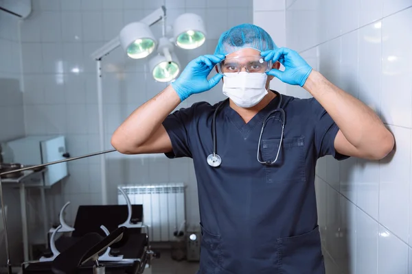 Man van de chirurg in operatiekamer met medische hulpmiddelen zet bril — Stockfoto