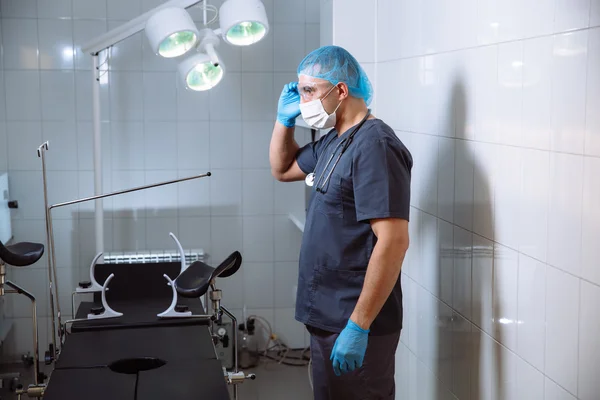 Chirurgo uomo in sala operatoria con strumenti medici mette occhiali — Foto Stock