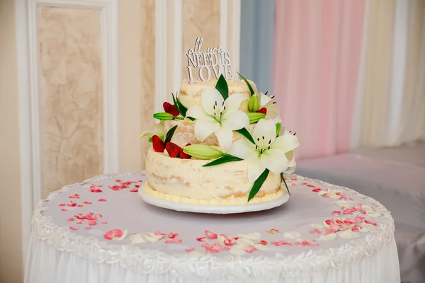 Multilevel sweet wedding cake with decorative flowers on white table — Stock Photo, Image